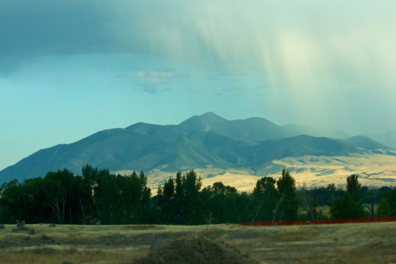 Rain coming down from the clouds over mountains.